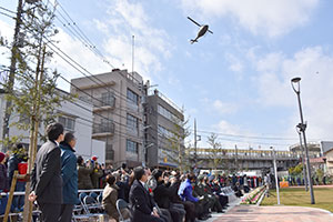 飛んでくるヘリを見つめる関係者